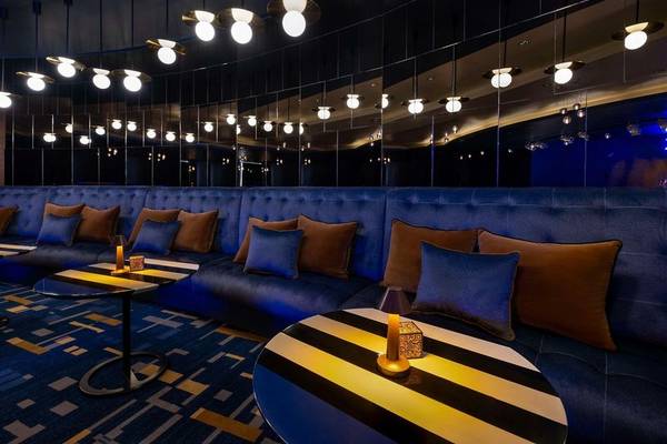 Loungebereich im Hyatt Regency Oryx Doha mit blauen Sofas, gestreiften Tischen und Hängelampen.