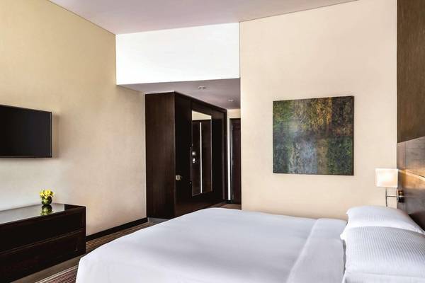 Schlafzimmer im Hyatt Regency Oryx Doha mit Doppelbett, Fernseher und Wanddekoration.