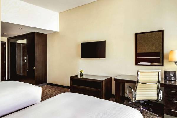 Hotelzimmer im Hyatt Regency Oryx Doha mit zwei Betten, Schreibtisch und Fernseher.