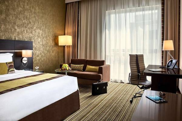 Suite-Zimmer im Hyatt Regency Oryx Doha mit Bett, Sofa, Schreibtisch und Fenstern.