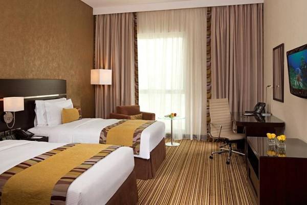 Doppelzimmer im Hyatt Regency Oryx Doha mit zwei Betten, Schreibtisch, Stuhl und Fernseher.