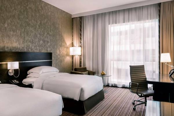 Doppelzimmer im Hyatt Regency Oryx Doha mit zwei Betten, Schreibtisch und Fenstern.