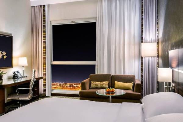 Innenansicht eines Zimmers im Hyatt Regency Oryx Doha mit Blick auf die Stadt bei Nacht.