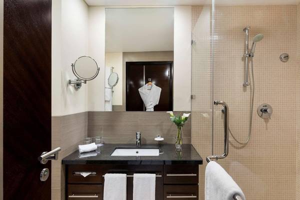 Badezimmer im Hyatt Regency Oryx Doha Hotel mit Spiegel, Waschbecken, Handtüchern und Dusche.