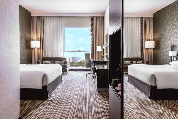 Innenansicht eines Hotelzimmers im Hyatt Regency Oryx Doha mit zwei Betten, Schreibtisch und Ausblick auf die Stadt.