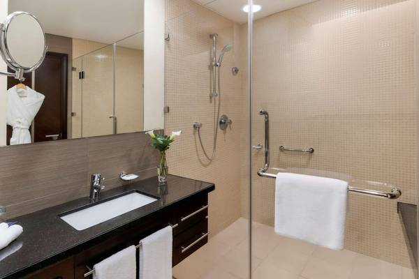 Badezimmer mit einer Dusche, Spiegel, Waschbecken und Handtüchern im Hyatt Regency Oryx Doha