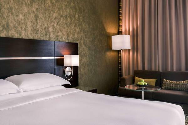Schlafzimmer im Hyatt Regency Oryx Doha mit einem Bett, zwei Lampen, einem Couchtisch und einer Couch.