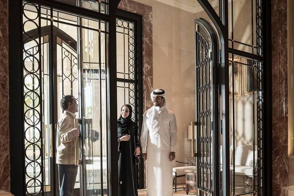 Eingangsbereich des Four Seasons Hotel Doha mit drei Personen, die durch eine Glastür schauen