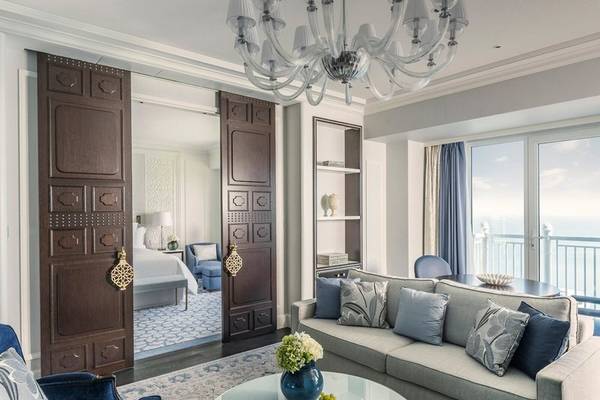 Wohnzimmer des Four Seasons Hotel Doha mit großem Sofa, Tisch und Blick auf das Meer.