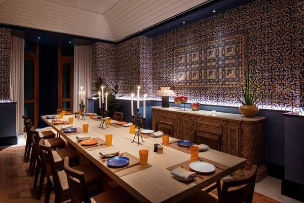 Ein elegantes Esszimmer im Four Seasons Hotel Doha mit blauen und weißen Tellern, Kerzen und gemusterten Wänden.