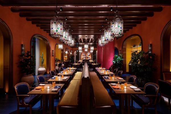 Innenansicht des Restaurants im Four Seasons Hotel Doha mit farbenfrohen Wänden und hängenden Lampen.