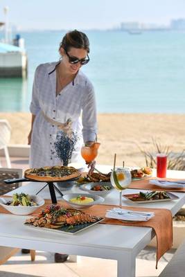 Ein Buffet auf dem Tisch am Strand im Four Seasons Hotel Doha mit verschiedenen Gerichten.