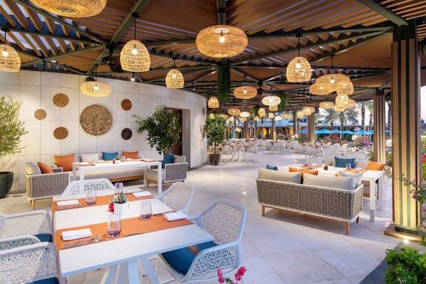 Innenbereich des Restaurants im Four Seasons Hotel Doha mit Tischen, Stühlen und dekorativen Lampen.