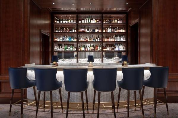 Innenansicht der Bar im Four Seasons Hotel Doha mit Barhockern und Theke.