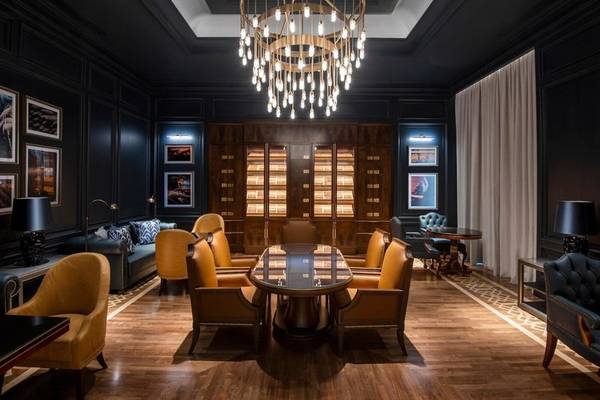 Rauchsalon im Four Seasons Hotel Doha mit zentralem Kronleuchter und Holzmöbeln.