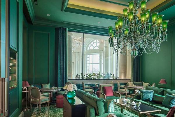 Inneneinrichtung des Four Seasons Hotel Doha mit grünen Wänden, einem großen Kronleuchter und luxuriösen Möbeln.