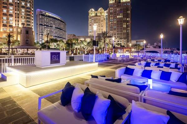 Außenbereich des Four Seasons Hotel Doha Lounge bei Nacht mit beleuchteten Sofas und Palmen.