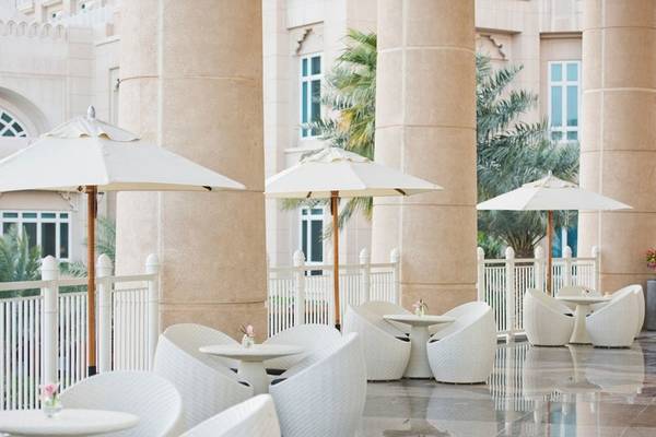 Außenterrasse des Four Seasons Hotel Doha mit weißen Möbeln und Sonnenschirmen.