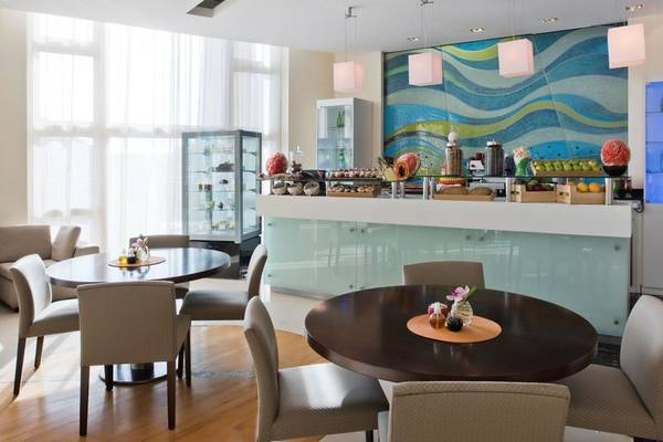 Frühstücksraum im Four Seasons Hotel Doha mit bunter Wand, Tischen und Stühlen.
