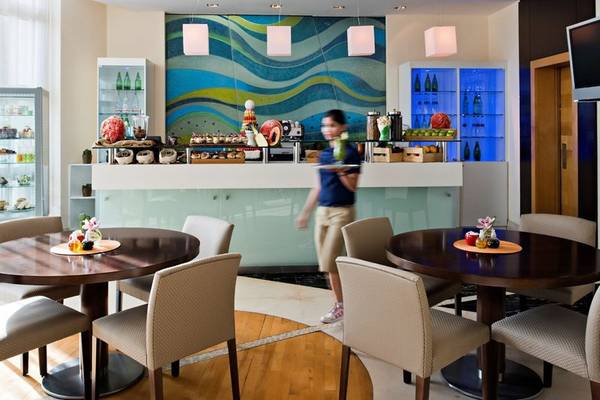 Lounge-Bereich des Four Seasons Hotel Doha mit einer Frau, die ein Tablett serviert.