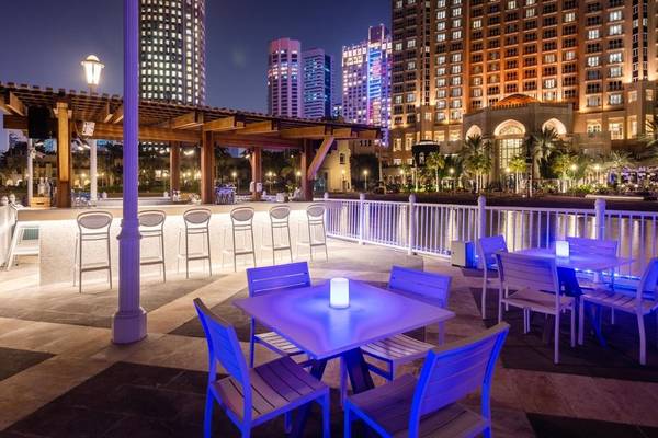 Abendliche Hotelterrasse des Four Seasons Hotel Doha mit beleuchteten Tischen und Stühlen.