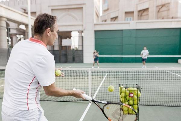 Tennisspieler im Four Seasons Hotel Doha schlägt einen Ball in Richtung Ballkorb.