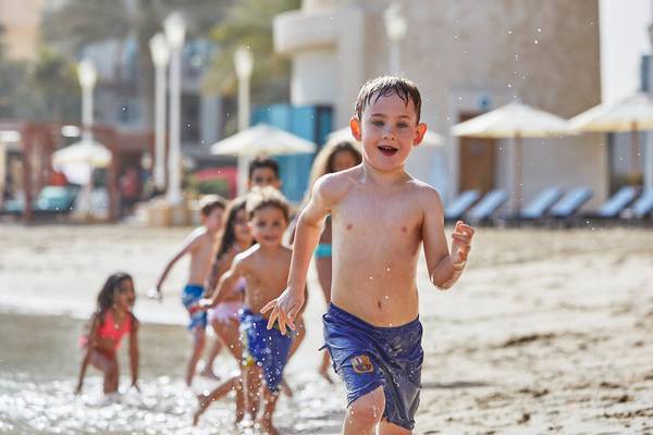 Kinder laufen am Strand vor dem Four Seasons Hotel Doha