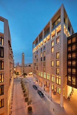 Abendansicht des Mandarin Oriental Doha Hotels mit hell beleuchteten Fassaden und Autos vor dem Gebäude.