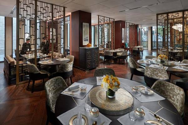 Inneneinrichtung des Restaurants im Mandarin Oriental Doha mit runden Tischen, Stühlen und Tischdekorationen.