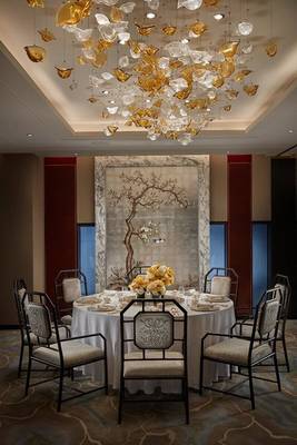 Esszimmer im Mandarin Oriental Doha mit goldenen Kronleuchter und Tischdekoration.