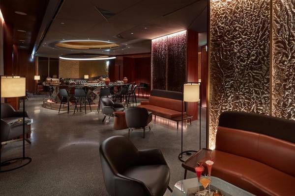 Innenraum des Mandarin Oriental Doha, Loungebereich mit braunen Ledersofas, Tischen und Stühlen.