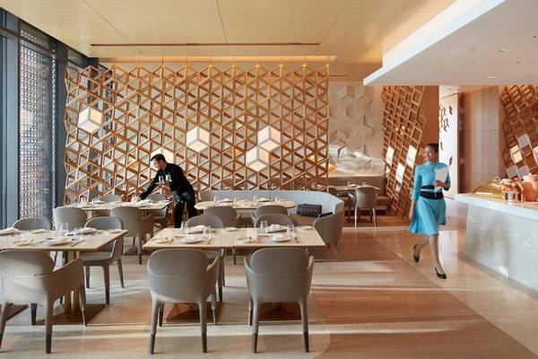 Innenansicht des Restaurants im Mandarin Oriental Doha mit geometrischen Wandverkleidungen und geschäftigen Kellnern.