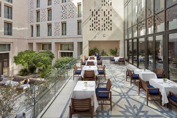 Außenterrasse des Mandarin Oriental Doha Hotels mit gedeckten Tischen und Stühlen.