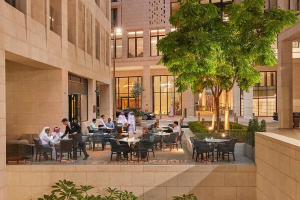 Außenbereich des Mandarin Oriental Doha Hotels mit Gästen, die in einem offenen Restaurantbereich sitzen