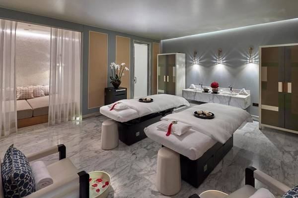 Massageraum im Mandarin Oriental Doha mit zwei Behandlungstischen, Sesseln und einer Badewanne.
