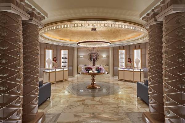 Lobby des Mandarin Oriental Doha mit Marmorboden, Kronleuchter und zwei Angestellten an den Schaltern.