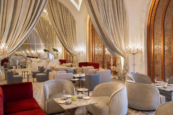 Lounge-Bereich im Raffles Doha Hotel mit eleganten Möbeln, Deckenleuchten und prächtigen Vorhängen.