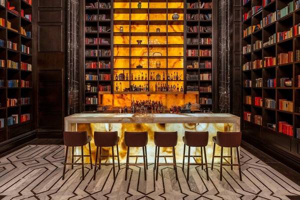 Bar in der Bibliothek des Raffles Doha mit Marmortheke und Bücherregalen.