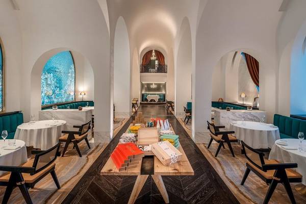 Innenansicht des Restaurants im Raffles Doha mit runden Tischen, Bänken und dekorativen Elementen.