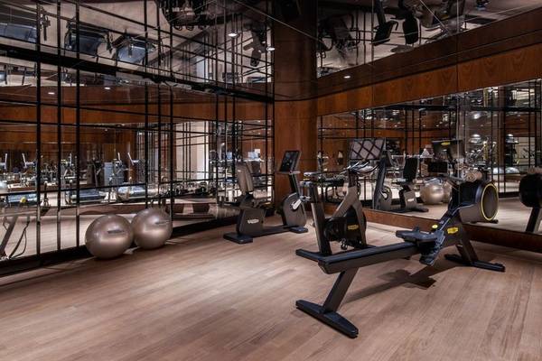 Fitnessstudio im Raffles Doha Hotel mit Glaswänden und moderner Trainingsausrüstung.