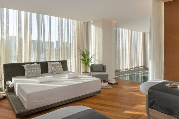 Schlafzimmer im Raffles Doha Hotel mit zwei Betten, Fenstern und einem kleinen Pool.