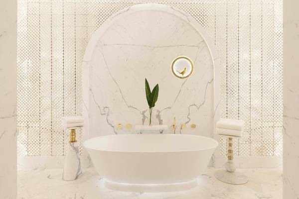 Ein Badezimmer im Raffles Doha Hotel mit einer weißen Badewanne und Marmorboden.