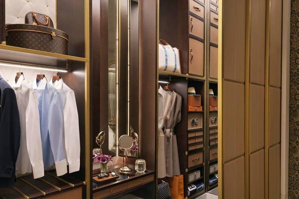 Ein geräumiger Kleiderschrank im Raffles Doha Hotel mit Spiegel, Regalen und Accessoires.