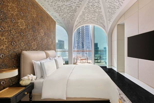 Schlafzimmer im Raffles Doha mit großem Bett, luxuriöser Einrichtung und Aussicht auf die Stadt.
