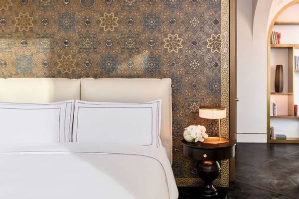 Ein luxuriöses Schlafzimmer im Raffles Doha Hotel mit einem weißen Bett und blauen Wandverkleidungen.