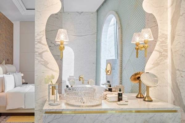 Das Badezimmer des Raffles Doha Hotels mit weißem Marmor und goldenen Details.