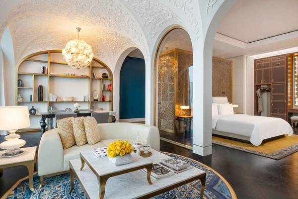 Innenansicht des Raffles Doha Hotels mit Wohnzimmer, Couch, Tisch und Lampe.