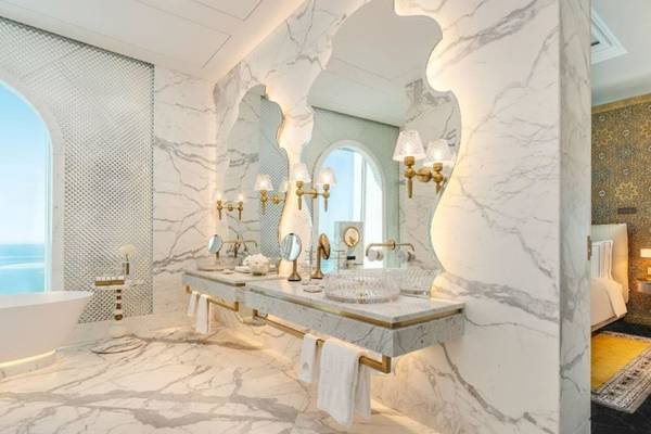Luxuriöses Badezimmer im Raffles Doha mit Marmorwänden, Doppelwaschbecken und großen Spiegeln.