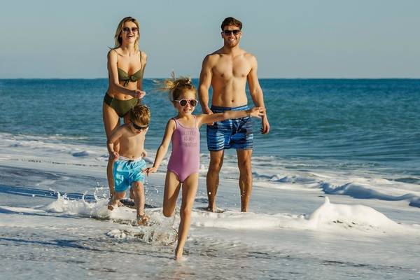 Familie am Strand vor dem Grand Park Lara Hotel, alle in Badekleidung und sonnigem Wetter