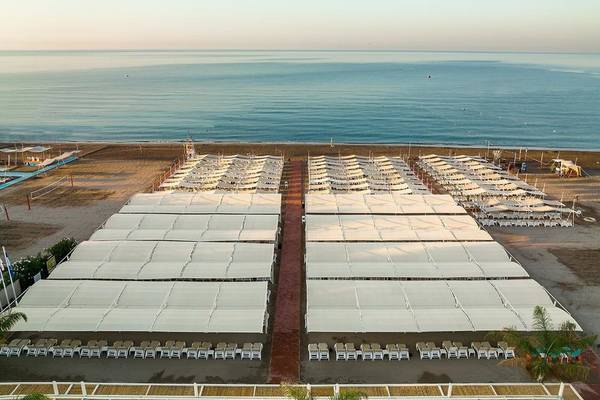 Luftaufnahme des Grand Park Lara Hotels mit Strand und vielen Sonnenschirmen und Liegen.